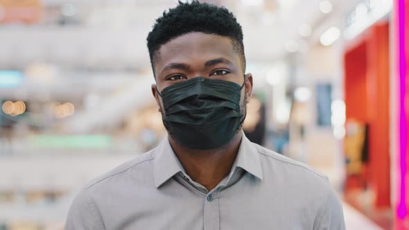 Closeup Young African American Man in Protective Medical Mask Walking in Mall Looking at Camera