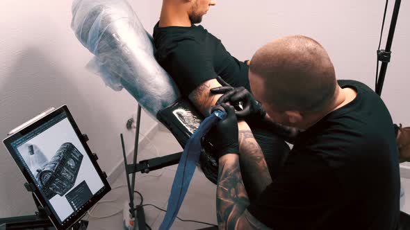 Male Tattoo Artist Tattooing a Client