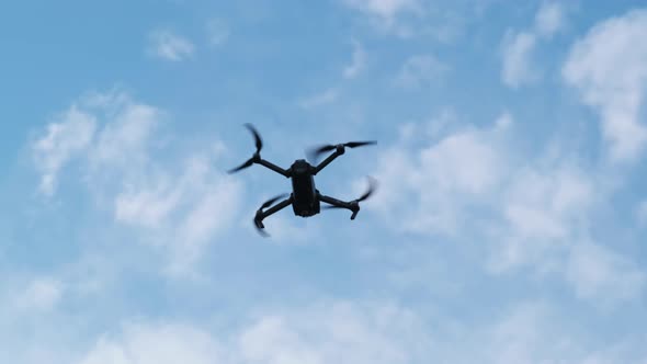 Drone Hangs in the Air Against the Blue Sky, View From Below. Slow Motion