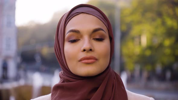 A Young Beautiful Muslim Woman Looks Seriously at the Camera in a Street in an Urban Area