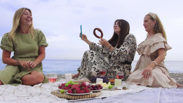 Funny Women Take Selfies with Bagels on the Beach While Having a Picnic