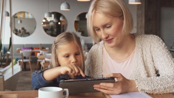 Mother and Daughter Use Tablet at the Cafe