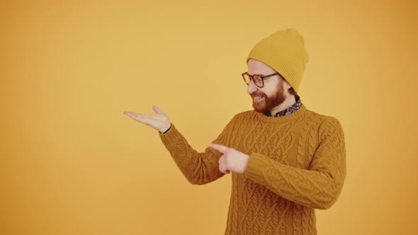 Young Smiling Caucasian Man Holds His Hand Open and Points at It Direction Isolated Copy Space