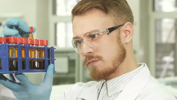 A Young Laboratory Worker Looks Carefully at Each Test Tube