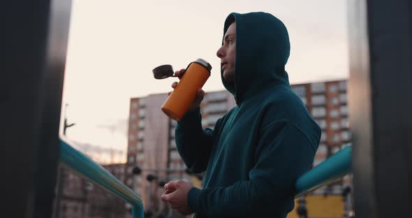 Man on the Sports Ground Drinks a Tea From Thermos