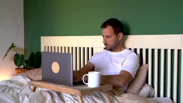 Man closing laptop, drinking coffee, looking uneasy