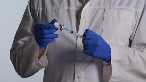 Medical Worker Hand with Surgical Gloves Showing Vial with Vaccine of Coronavirus. Doctor Dials the