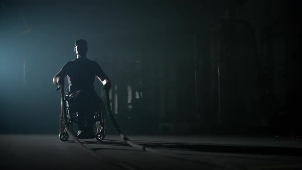 Disabled Man in Wheelchair Performs Exercises with Battle Ropes Crossfit Endurance Training Athlete