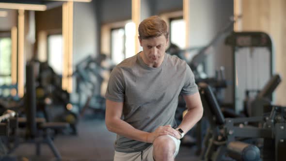 Attractive Fitness Man Warming Up Legs at Gym. Sportsman Making Squats at Gym. alt