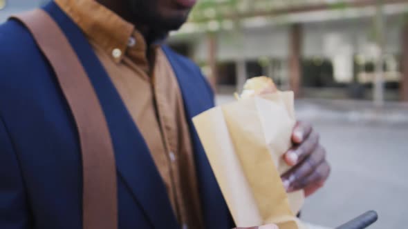 African american businessman eating sandwich in city street
