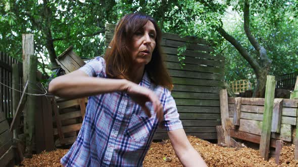 Mature woman using gardening fork in the garden