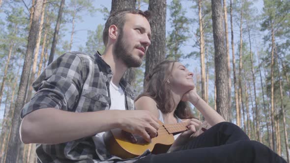 Portrait Attractive Bearded Young Man Playing Ukulele While Pretty Young Happy Woman Sitting