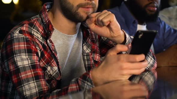 Men in Pub Worrying About Winning Sport Lottery, Checking Bets on Smartphone