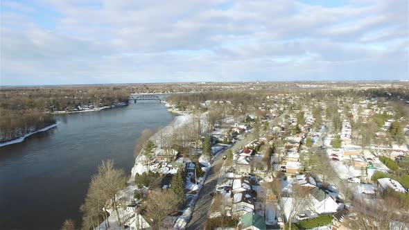 Aerial view of a neighborhood in the winter surrounded by water on a sunny day