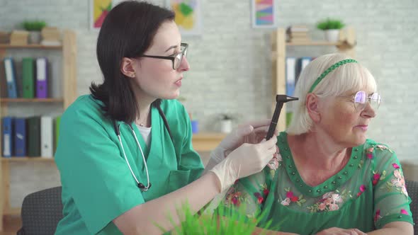 Otolaryngologist Examines the Ear of an Old Woman with the Help of an Otoscope