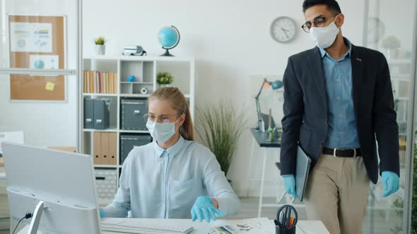 Arab Man in Mask and Gloves Leaving Office Doing High-five with Caucasian Woman Colleague