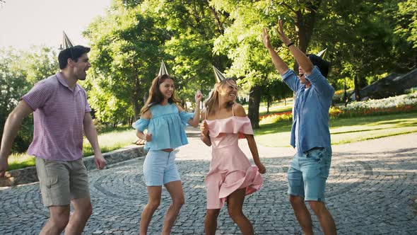 Young Friends in Party Hats are Smiling Having Fun Shower with Confetti and Dancing in Green