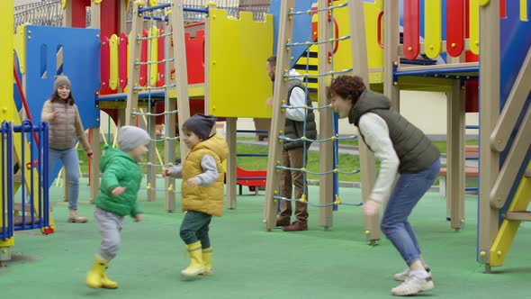 Caucasian Parents and Kids Playing Tag at Playground