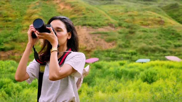 Young Asian female traveler is enjoying the beautiful scenery of the mountains and the green fields.