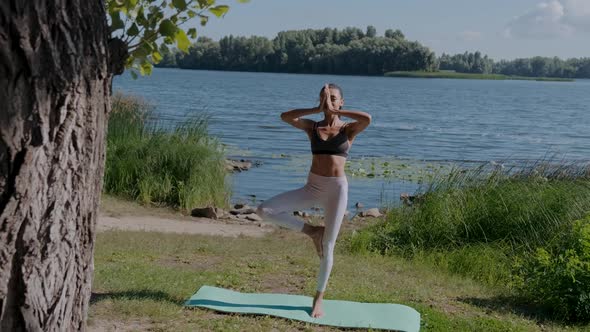 Full Length Portrait of Healthy Young Woman Doing Yoga Balance Exercise on the River Bank