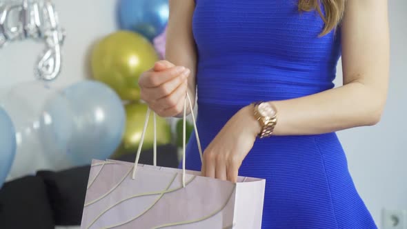 Close Up of Fit Woman in Blue Dress Reaching Into Birthday Gift Bag at Birthday Party