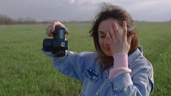 Beautiful Young Woman Makes a Photos with a Camera on the Field