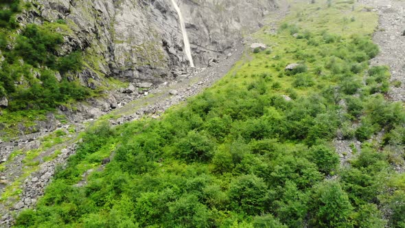 Camera Approach To Rock with Waterfall Flowing Into Mountain River. Shooting From Quadrocopter of