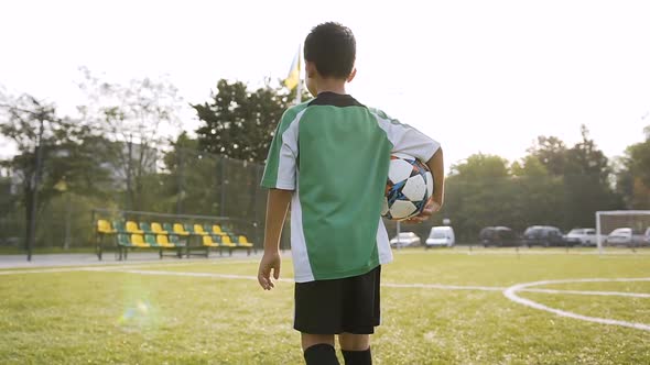 Little Boy Walking with Soccer Ball in the Hand