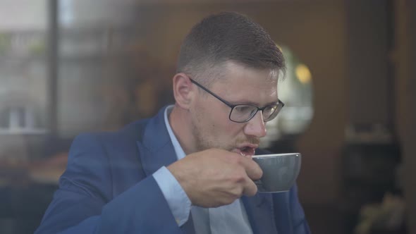 Confident Male CEO Drinking Coffee in Cafe. Portrait of Successful Caucasian Businessman Enjoying