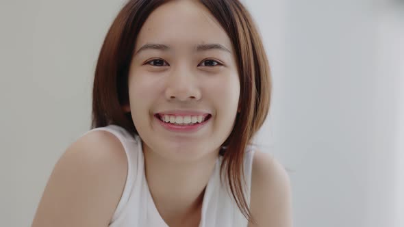 Portrait of smiling Asian girl with natural makeup and healthy smooth skin looking at camera.