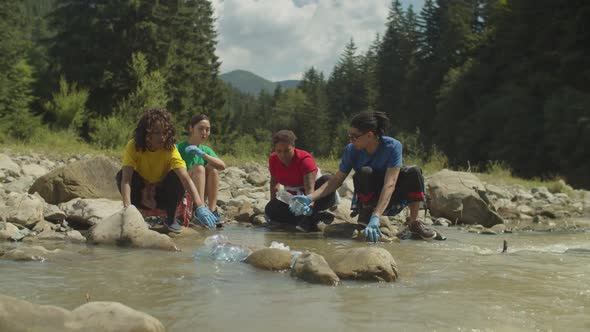 Diverse Multiethnic Eco Volunteers Cleaning Up Plastic Waste From Mountain River