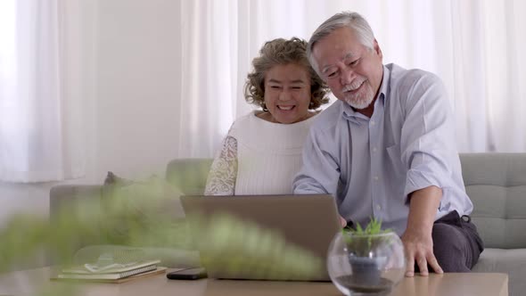 Couple Asian elderly video conferent online with laptop in living room.