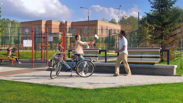 Happy Young Couple Stopped to Rest on a Bench After Cycling on a Sunny Summer Day