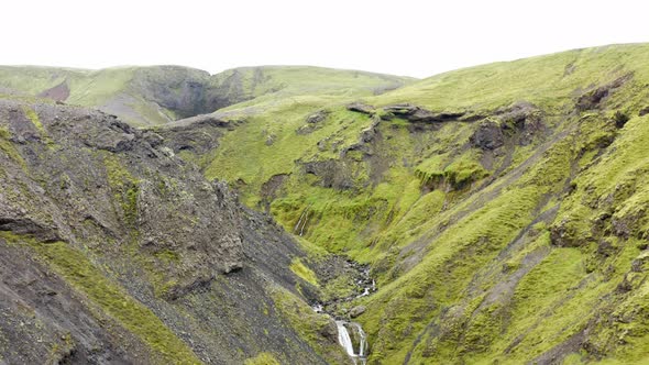Flying Through Green Mossy Canyons With Flowing Stream At Nauthúsagil Waterfall In Iceland. Aerial