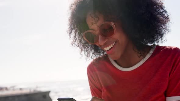 Woman using mobile phone on the beach in sunshine 4k