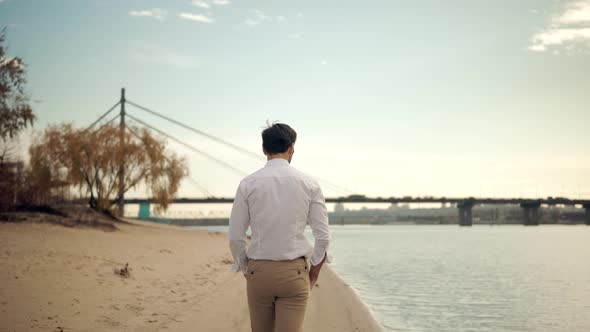 Man Walking On City Beach. Guy In Sunglasses Walks On Sand And Dreaming. Man Walking On Sand Beach.