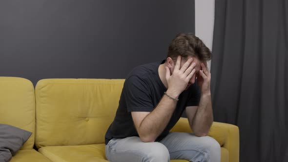 Unshaven Guy on Sofa Suffering From Headache