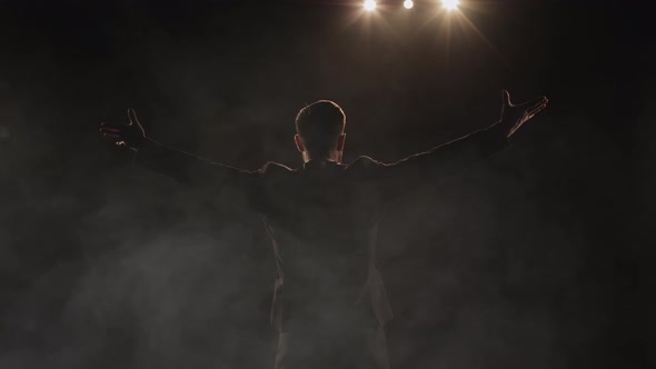 A Man is Standing on Stage and Waving His Hands