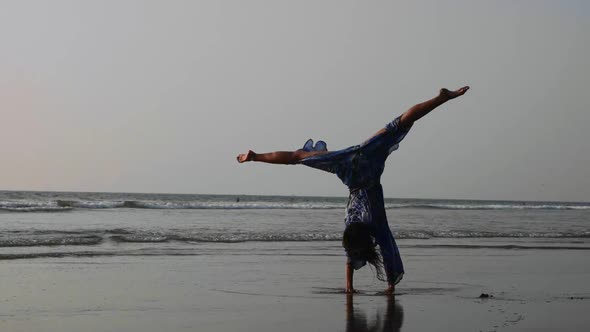 Young Gymnast Woman Doing Handspring on Sandy Beach