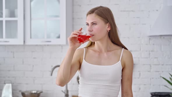 Young woman with juice. Close up on fitness young woman drinking juice in kitchen