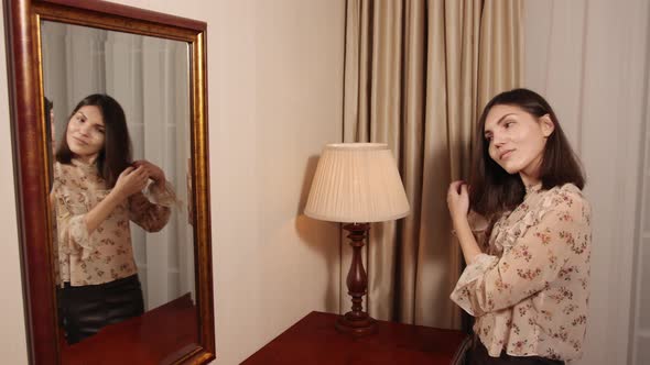 Beautiful Young Woman is Combing Her Hair Smiling While Looking Into Mirror