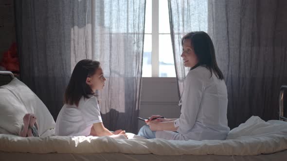 Doctor and Little Patient Sitting Opposite Each Other on Hospital Bed