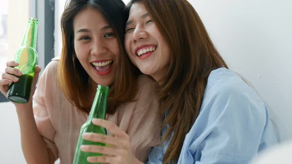 Young Asian young woman lesbian couple clinking bottles of beer in the bedroom.