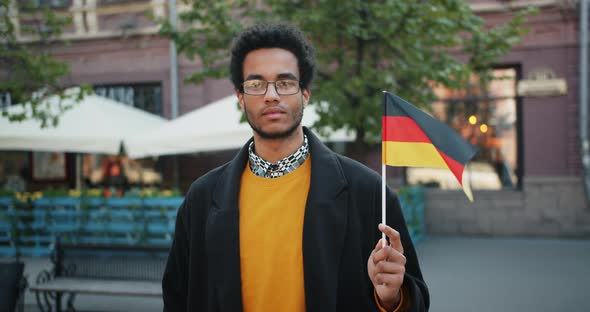 Portrait of Handsome African American Man Holding German Flag in the Street