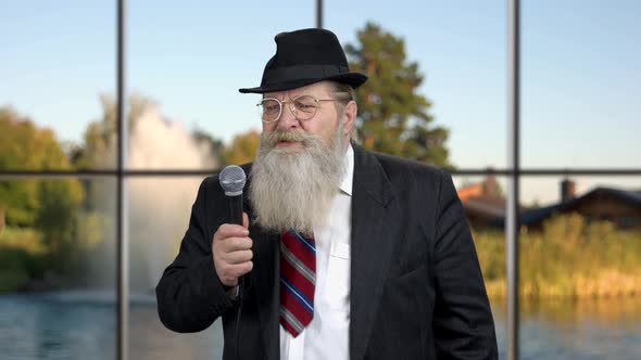 Senior Man in Business Suit Talking Into Microphone.