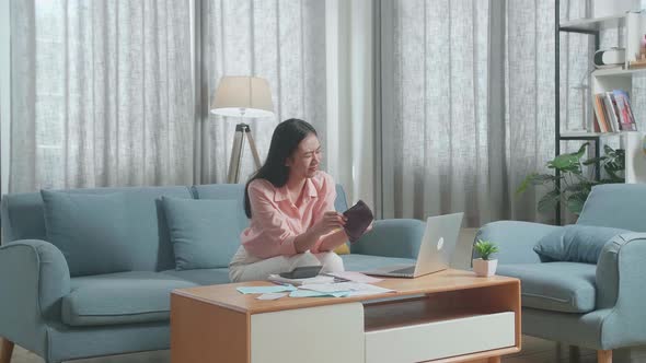 Asian Woman Looking At The Bill On Hand And Checking Money On The Purse Before Shaking Her Head