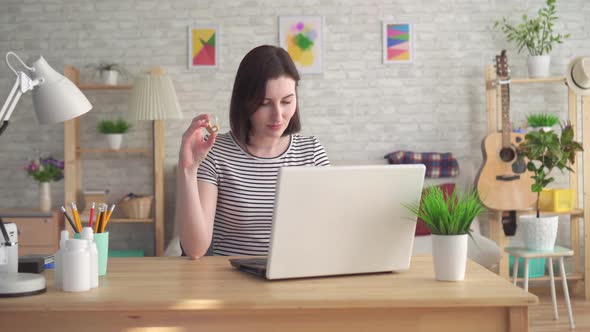 Young Woman Looking for Information on the Internet in a Laptop and Holding a Hearing Aid