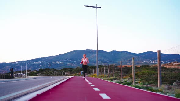 Full Length View Athletic Female Jogger Running Bike Lane Near Road with Mountain Background