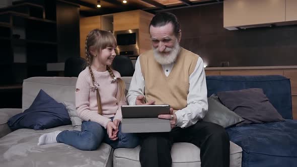 Girl Sitting on the Couch with Her Respected Bearded Senior Grandfather