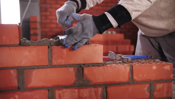 builder lays red brick close-up